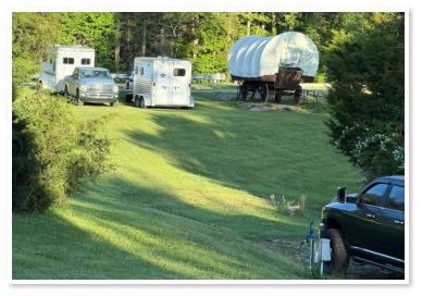 covered wagon with trucks and trailers parked beside it