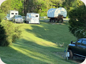 covered wagon with trucks and horse trailers parked beside it